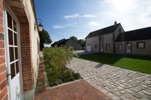 a brick house with a brick driveway next to a yard at Le parc de Crécy in Crécy-Couvé