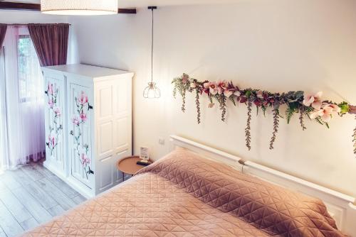 a bedroom with a bed with flowers on the wall at Pension La Roata in Gura Humorului