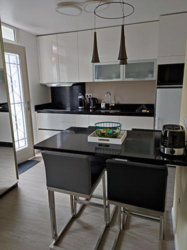 uma cozinha com uma mesa preta e cadeiras num quarto em Appartement avec terrasse - M4 Lucie Aubrac em Bagneux