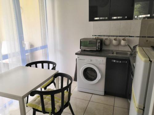 uma cozinha com uma máquina de lavar roupa e uma mesa com cadeiras em Charmant T2 en rez de chaussée em Balaruc-les-Bains