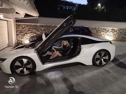 a woman sitting in a white car with its door open at B&B Bellavista Exclusive in zona centrale con piscina riscaldata e Jacuzzi vista lago LA COLAZIONE viene servita in una pasticceria rinomata ed esclusiva esterna alla struttura in Desenzano del Garda