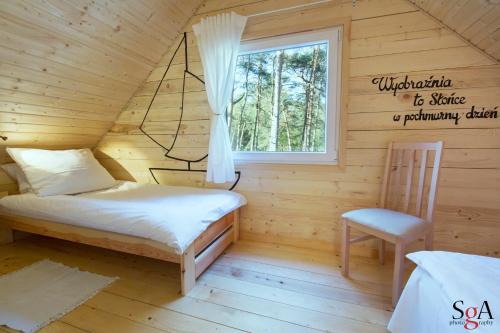 a bedroom in a log cabin with a bed and a chair at Morska Fala Domki in Pobierowo
