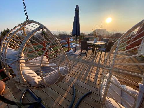 a swing on a deck with a table and an umbrella at Szőlőhegy Vendégház Sümeg in Sümeg