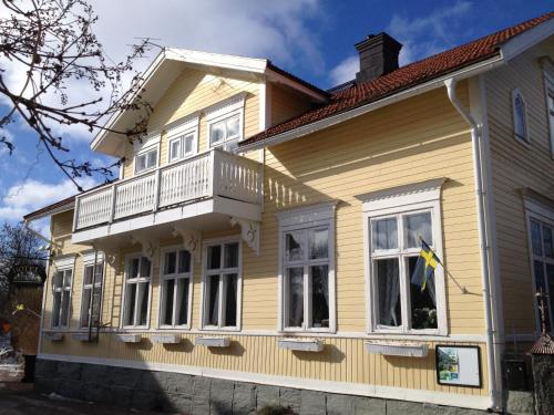 a yellow house with a balcony on top of it at Hotell Floras Trädgård in Öregrund