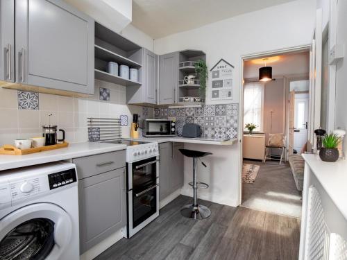 a kitchen with white cabinets and a washer and dryer at Central cosy home 5 minutes walk from Shrewsbury - Pass the Keys in Shrewsbury