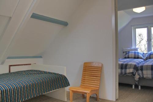 een slaapkamer met een bed, een stoel en een raam bij Eb in Callantsoog