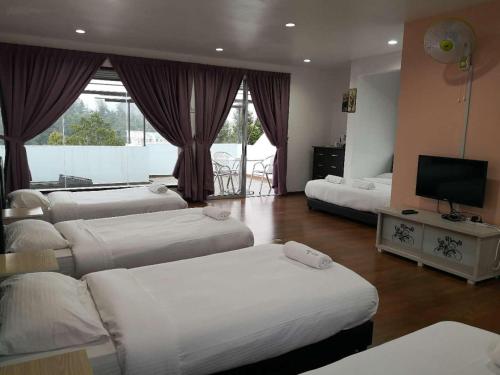 a hotel room with three beds and a flat screen tv at Dear Dino Villa Cameron Highlands in Cameron Highlands