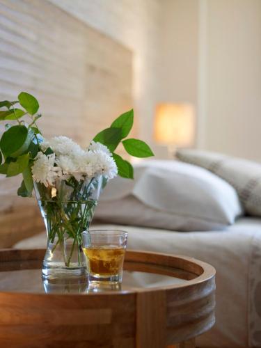 a vase of flowers on a table with a glass of whiskey at Belle Helene Hotel in Vathi, Mani