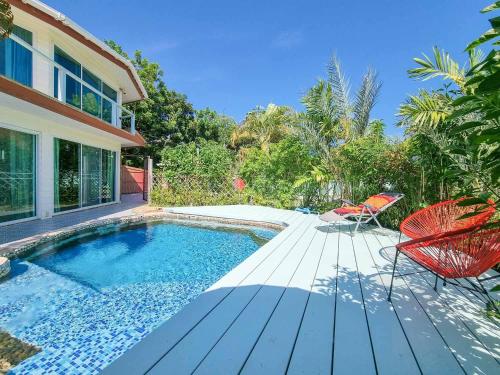 a swimming pool with chairs and a house at Tina's Living Paradise - Guesthouses with private pool in Ban Phe