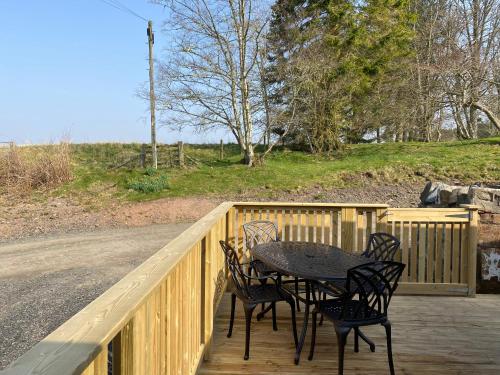 a table and four chairs on a wooden deck at Partridge Lodge with Hot Tub in Forgandenny