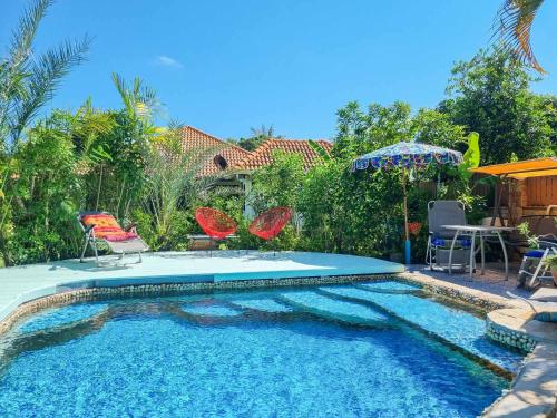a swimming pool with chairs and an umbrella at Tina's Living Paradise - Guesthouses with private pool in Ban Phe