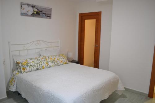 1 dormitorio con cama blanca y puerta de madera en Valle del Genil, en Pinos Genil
