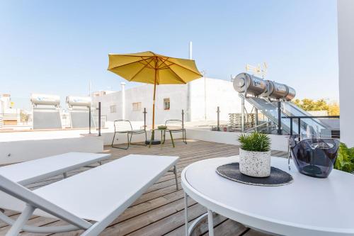 un patio con mesas y una sombrilla en el techo en Precioso Ático de diseño, gran Terraza y Garaje en pleno centro, en Sevilla