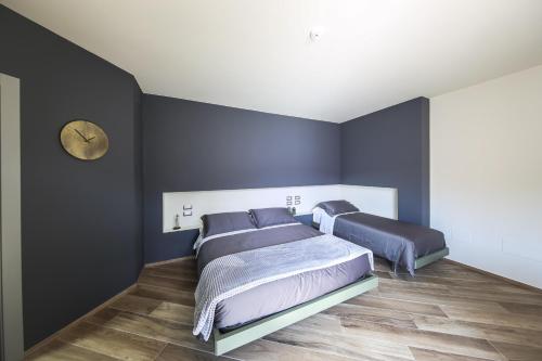 a bedroom with two beds and a clock on the wall at Vicolo Malavolta 7 Rooms and Suites in Pedaso