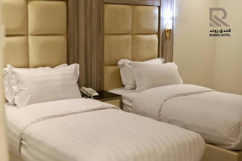 two beds in a hotel room with white sheets and pillows at فندق روند in Hafr Al Baten