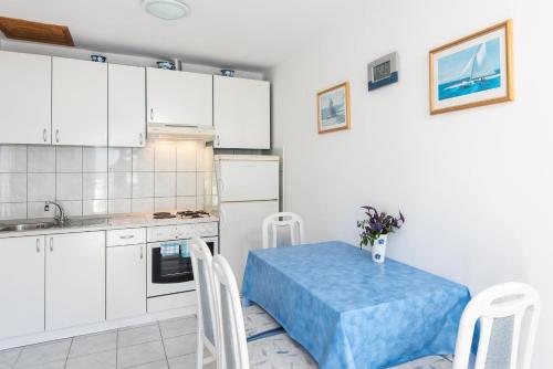 una cocina con armarios blancos y una mesa y sillas azules en Bella Perna Beachfront Apartments, en Kućište