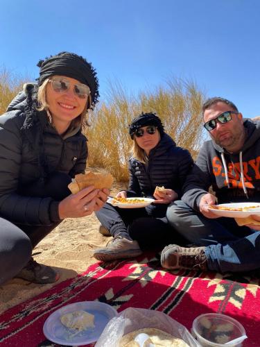 a group of people sitting on the beach eating food at wadi rum land mars in Wadi Rum