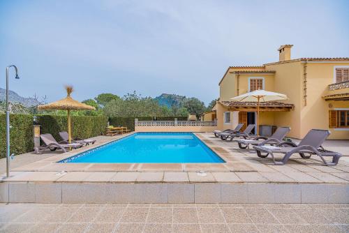 a swimming pool with chairs and umbrellas next to a house at Can Pansa in Port de Pollensa