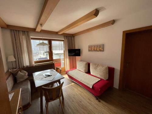 ein Wohnzimmer mit einem roten Sofa und einem Tisch in der Unterkunft Gästehaus Garber in Stumm