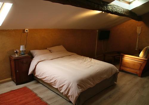 1 dormitorio con 1 cama grande y pared de madera en Logis des Brousses, en Lhommaizé