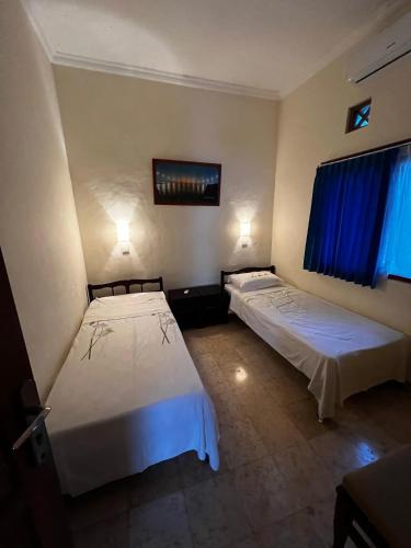 two beds in a room with blue curtains at Villa Mola Mola in Candidasa