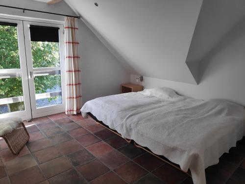 1 dormitorio con cama y ventana grande en Østergård Kultur B&B en Læsø
