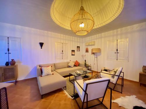 a living room with a couch and chairs and a chandelier at Villa Calma - Vue Mer in Al Ḩaddādah