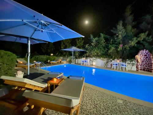 a swimming pool with chairs and umbrellas next to a pool at Villa Calma - Vue Mer in Al Ḩaddādah
