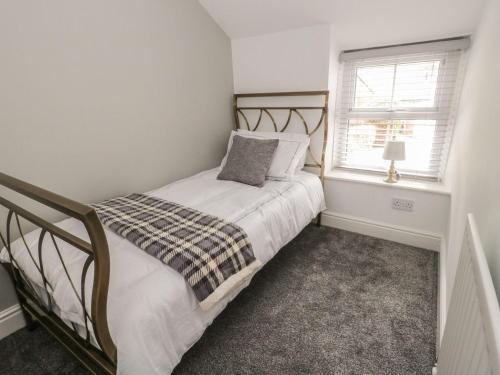 a small bedroom with a bed and a window at 4 Bronrallt in Penmaen-mawr