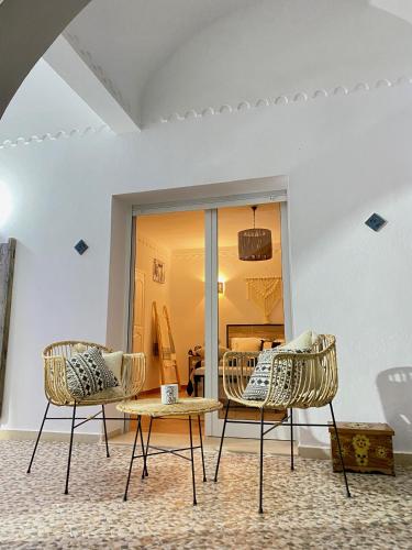 two chairs and a table in front of a room at Villa Calma - Vue Mer in Al Ḩaddādah