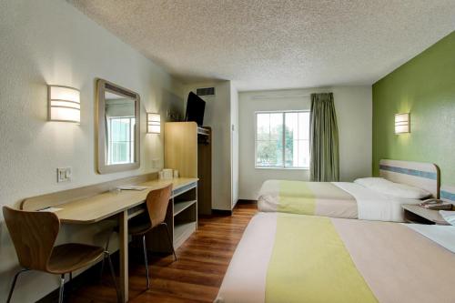 a hotel room with two beds and a desk at Super 8 by Wyndham Aurora East in Aurora