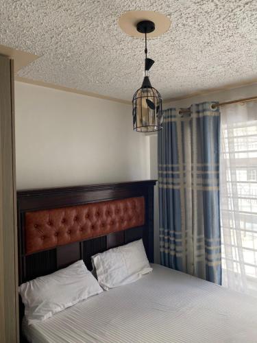 1 dormitorio con cama y lámpara de araña en Andyhill Studio Apartment -Tsavo Embakasi Near Sgr, en Nairobi