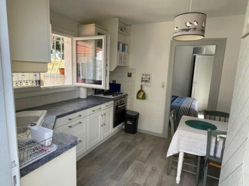 cocina con armarios blancos, mesa y comedor en Adorable petite maison à 400m de la mer, en Saint-Georges-de-Didonne