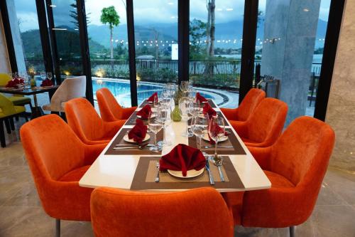 a dining room with a table and orange chairs at Cami Riverside Resort Da Nang in Da Nang