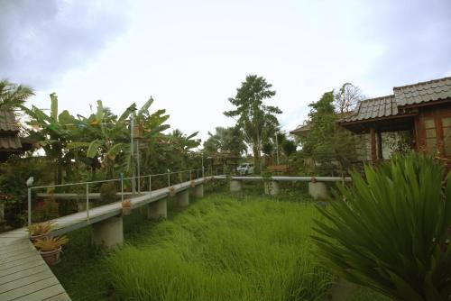 a walkway in a yard with grass and trees at เรือนไทยใจสุขเอ๋ย in Ban Bang Wa
