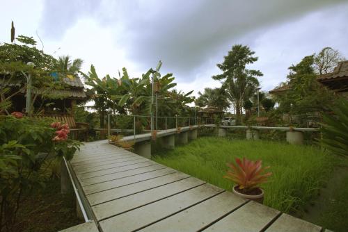 a wooden walkway in a garden with plants at เรือนไทยใจสุขเอ๋ย in Ban Bang Wa