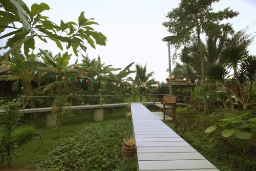 a walkway in the middle of a garden with trees at เรือนไทยใจสุขเอ๋ย in Ban Bang Wa