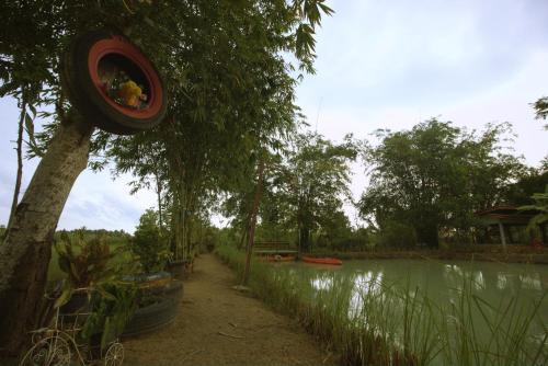 a tire hanging from a tree next to a river at เรือนไทยใจสุขเอ๋ย in Ban Bang Wa