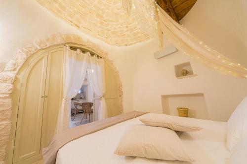 a white bedroom with a bed and a window at Trullo Love in Alberobello