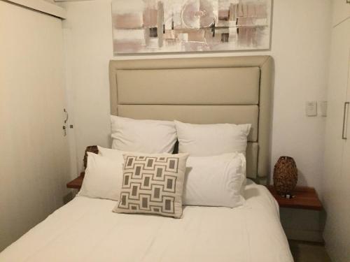 a bedroom with a bed with white sheets and pillows at Cabanas del Mar in Amanzimtoti