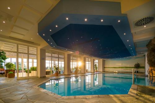 a swimming pool in a house with a large ceiling at Balmer See – Hotel•Golf•Spa in Balm