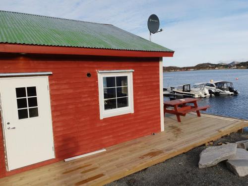 a red building with a dock and boats in the water at Havglimt in Oksvoll