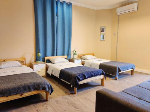 2 łóżka w pokoju z niebieskimi zasłonami w obiekcie Hostel Roks w mieście Hajfa