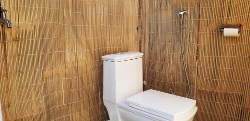 baño con aseo y pared de madera en The Raajas - Camp & Resorts en Rishīkesh