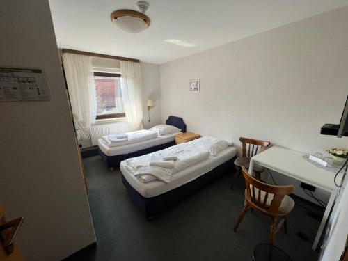 Habitación con 2 camas, mesa y escritorio. en Hotel Hennies Hannover Sehnde en Hannover