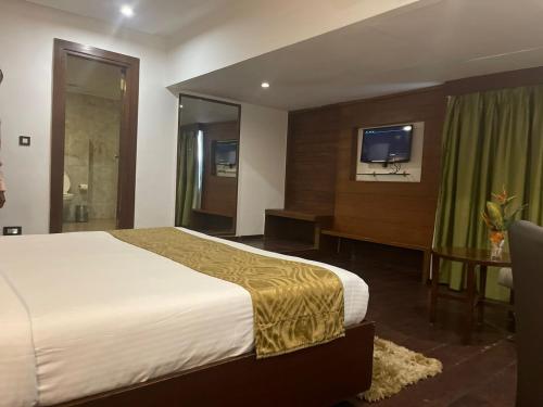ハイデラバードにあるTabla Pride Hotels & Spaのベッドとテレビが備わるホテルルームです。