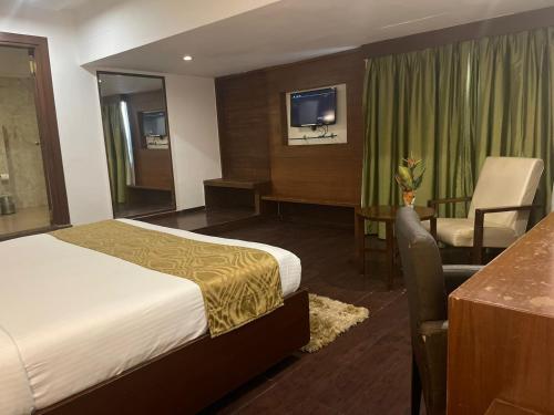 ハイデラバードにあるTabla Pride Hotels & Spaのベッド、椅子、デスクが備わる客室です。
