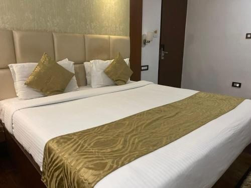 a bedroom with a large white bed with gold sheets and pillows at Tabla Pride Hotels & Spa in Hyderabad