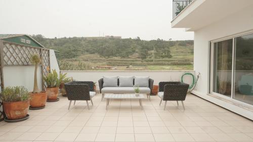 een patio met een bank en stoelen op een balkon bij Terraço dos Rabujas in Nazaré