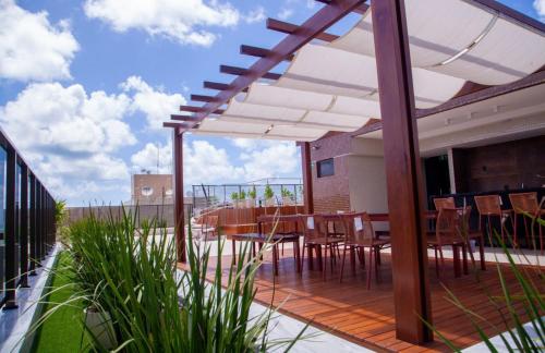 a patio with a table and chairs on a deck at APARTAMENTO MODERNO A 150m DA PRAIA DO CABO BRANCO in João Pessoa